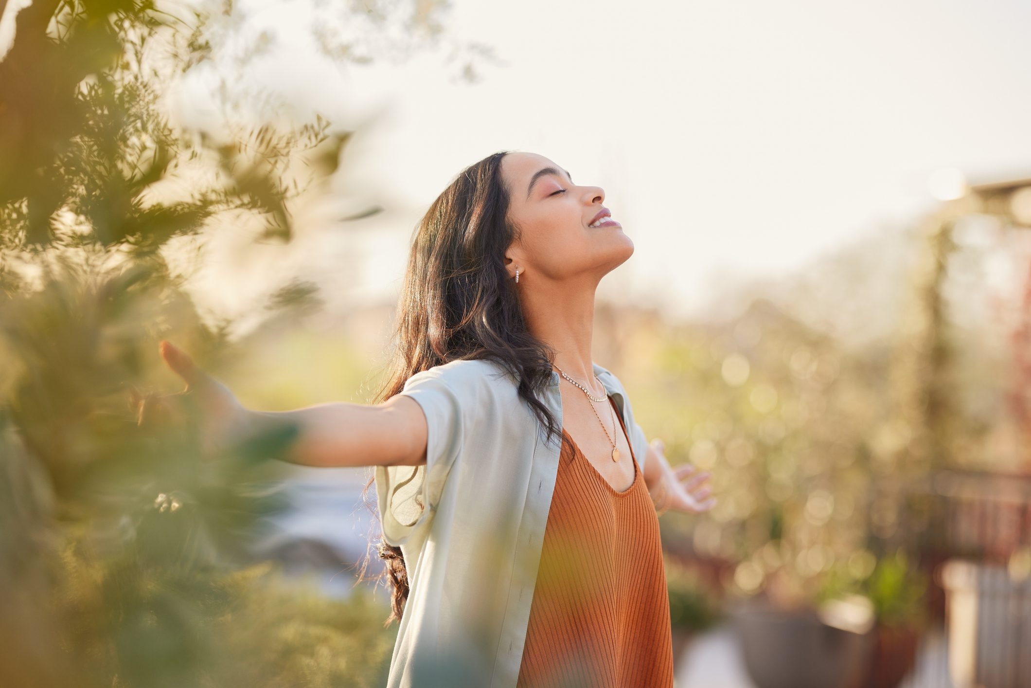 Woman enjoying sunlight with outstretched arms.