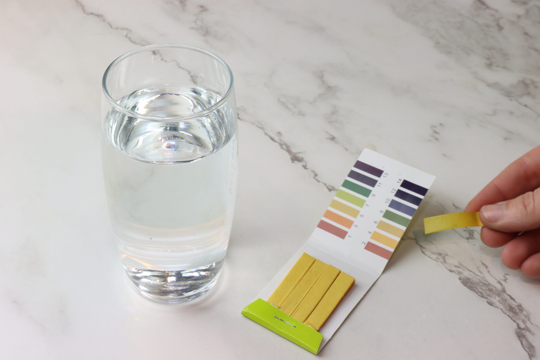 Glass of water with pH test strips.