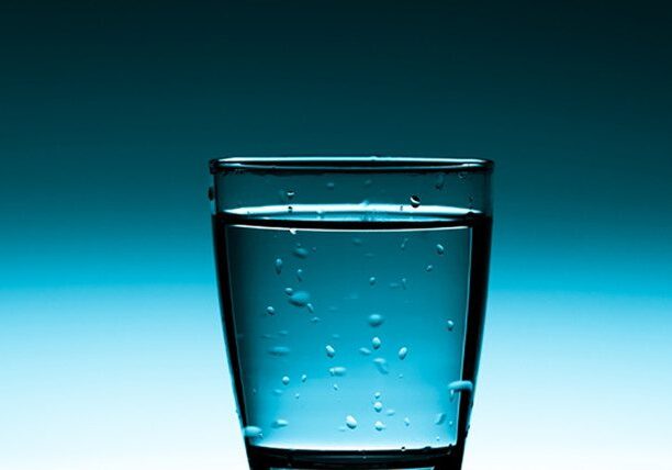 Glass of water with bubbles, blue background.