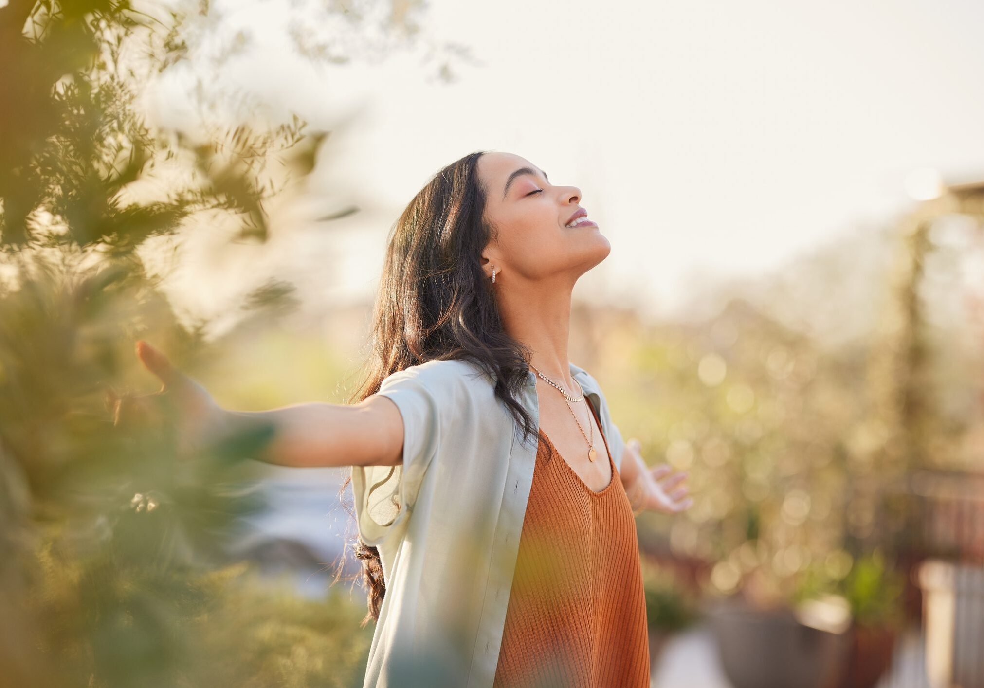 Woman enjoying sunlight with outstretched arms.