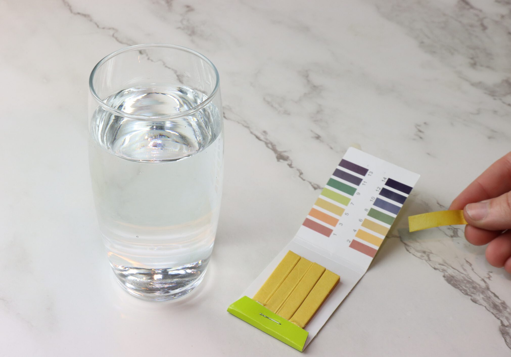 Glass of water with pH test strips.